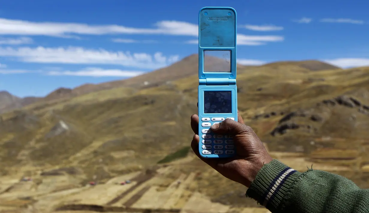 Alvaro Cabrera mencari sinyal di atas bukit untuk menghadiri kelas virtual di komunitas dataran tinggi Conaviri yang terpencil di Andes Peru, 24 Juli 2020. Sejak sekolah ditutup akibat COVID-19, Cabrera bersaudara bergantung pada ponsel guna mengakses platform “Belajar di Rumah”. (Carlos MAMANI/AFP)