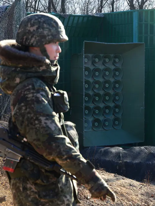 Tentara Korsel berjaga di dekat pengeras suara yang dipasang di sebelah selatan zona demiliterisasi, Yeoncheon, Jumat (8/1/2016). Pengeras suara tersebut memasang musik pop Korea, berita dan kritik atas Korea Utara ke arah perbatasan. (YONHAP/AFP)