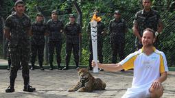 Fisioterapis Brasil, Igor Simoes Andrade, berpose dengan api olimpiade disamping seekor jaguar Juma dalam rangkaian parade api olimpiade di Manaus, Brasil, (20/6/2016). (Reuters/Marcio Melo)
