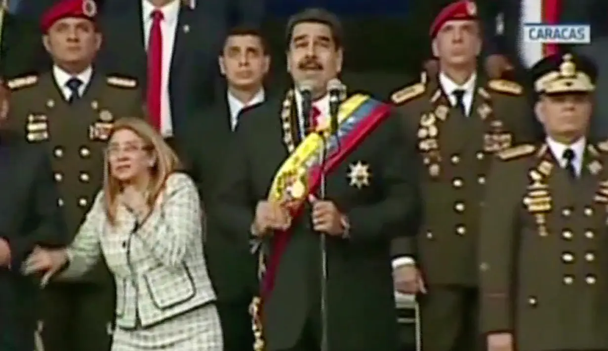 Presiden Venezuela Nicolas Maduro (tengah) didampingi istrinya Cilia Flores (kiri) diserang drone berpeledak, Caracas, Venezuela, Sabtu (4/8). Seorang pilot elite helikopter, Oscar Pérez mengklaim sebagai pelaku serangan. (Venezolana de Television via AP)