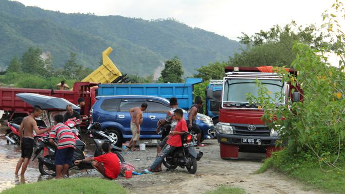 Sejumlah pemilik kendaraan memanfaatkan aliran sungai Bone untuk mencuci di kompleks Jembatan Talumolo II, Kelurahan Talumolo, Gorontalo, Senin (19/11). Tempat itu menjadi kawasan pencucian kendaraan bermotor yang gratis.  (Liputan6.com/Arfandi Ibrahim)
