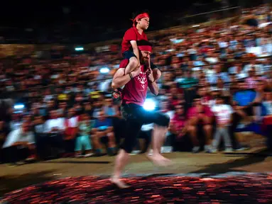 Seorang pria membawa anak lelaki di punggungnya sambil berjalan di atas bara api selama malam San Juan di San Pedro Manrique, Spanyol Utara, Minggu (24/6). Tradisi kuno Spanyol ini diperingati untuk menyambut musim panas. (AP Photo/Alvaro Barrientos)
