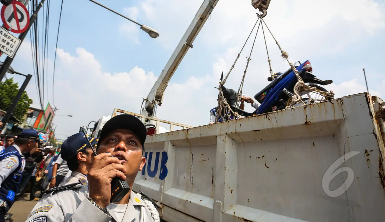 Petugas Dishub mengangkut sepeda motor dengan jaring saat razia parkir liar di kawasan Pasar Tanah Abang, Jakarta, Kamis (16/4/2015). Razia dilakukan untuk menciptakan kawasan yang tertib serta nyaman di kawasan Tanah Abang. (Liputan6.com/Faizal Fanani)