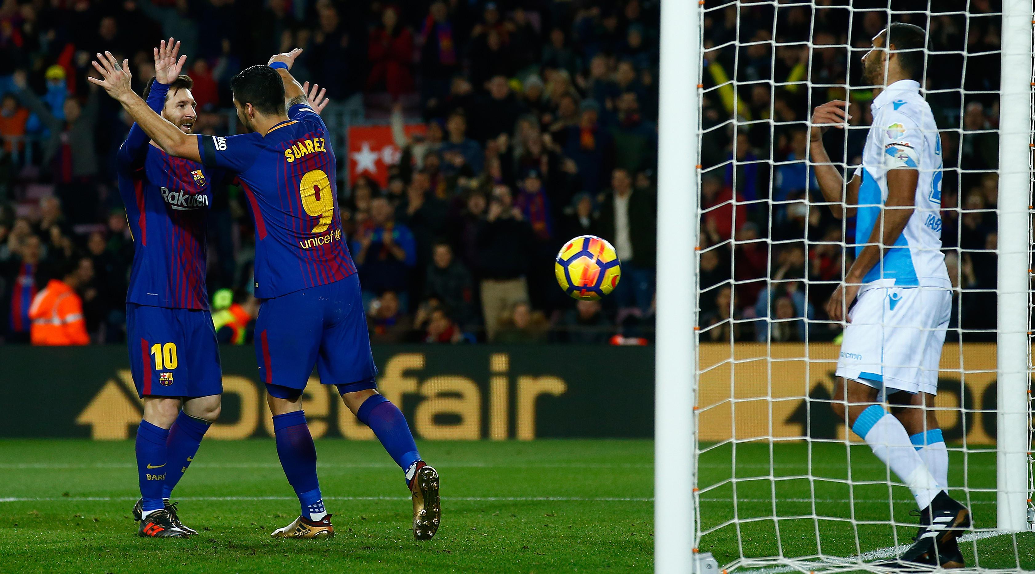 Pemain Barcelona, Lionel Messi merayakan gol rekan setimnya, Luis Suarez ke gawang Deportivo La Coruna pada pertandingan pekan ke-16 La Liga di Stadion Camp Nou, Senin (18/12). Barcelona unggul 4-0 lewat dua gol Suarez.  (AP/Manu Fernandez)