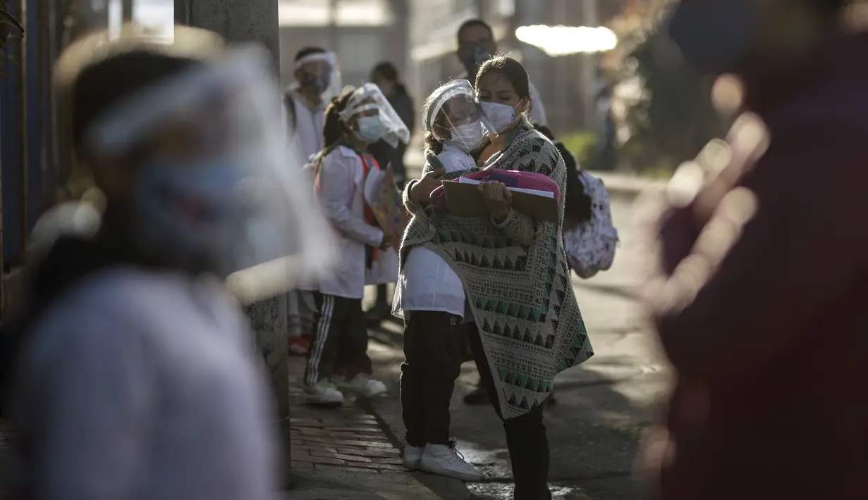 Orang tua menemani anaknya untuk memasuki Liceo Lunita, sebuah sekolah swasta, pada hari pertama kembali ke kelas tatap muka sejak Maret 2020 di Chia di pinggiran Bogota, Kolombia, Jumat (5/2/2021). Sejauh ini Kolombia melaporkan lebih dari 2,13 juta kasus Covid-19. (AP Photo/Ivan Valencia)