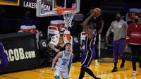 Pebasket Los Angeles Lakers, LeBron James, melakukan dunk di depan pemain Charlotte Hornets, LaMelo Ball. (AP/Marcio Jose Sanchez).