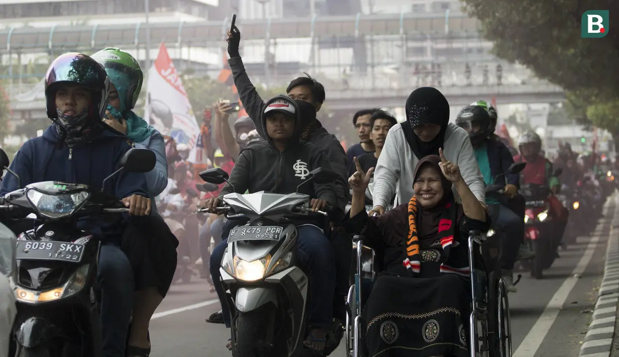 Suporter Persija Jakarta, The Jakmania, konvoi gelar Piala Presiden menggunakan kursi roda melintasi Jalan Thamrin, Jakarta, Minggu (18/2/2018). Persija meraih juara setelah mengalahkan Bali United. (Bola.com/Asprilla Dwi Adha)