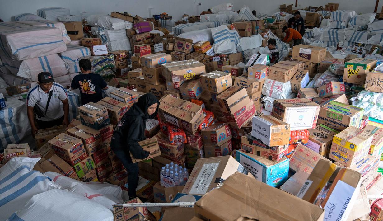 Bantuan logistik ini nantinya akan dibagi ke sejumlah wilayah terdampak banjir bandang Sumatera. Tampak dalam foto, para relawan mengemasi perlengkapan untuk dikirimkan ke daerah-daerah terdampak banjir di Badan Penanggulangan Bencana Daerah (BPBD) Sidoarjo, Provinsi Jawa Timur, pada Jumat 5 Desember 2025. (JUNI KRISWANTO/AFP)