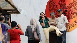 Warga berfoto di depan gambar Garuda Pancasila di Lapangan Kebagusan, Jakarta, Rabu (15/2). Jelang menggunakan hak pilihnya pada Pilkada, Ketua Umum PDI-P Megawati Soekarnoputri menggoreskan tinta pada salah satu gambar. (Liputan6.com/Helmi Fithriansyah)