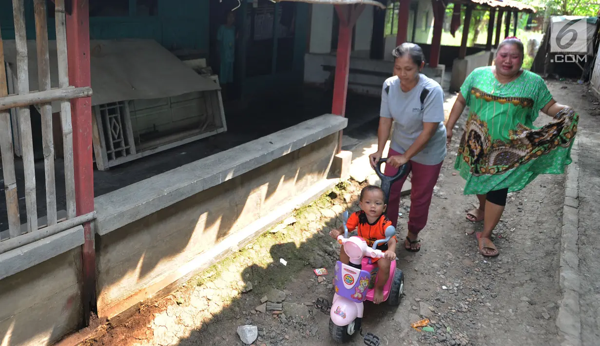 Warga mendorong anaknya yang sedang menaiki sepeda di kawasan Rawa Rengas, Kosambi, Tangerang, Banten, Selasa (2/7/2019). Sekitar 130 KK masih bertahan di rumahnya karena belum menerima ganti rugi dari perluasan landasan pacu atau Runway 3A Bandara Soekarno-Hatta. (merdeka.com/Arie Basuki)