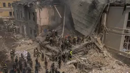 Petugas darurat dan penyelamatan bersama dengan petugas medis lainnya membersihkan puing-puing bangunan Rumah Sakit Anak Ohmatdyt yang hancur setelah serangan rudal Rusia di ibu kota Ukraina, Kyiv, pada tanggal 8 Juli 2024. (Roman PILIPEY/AFP)