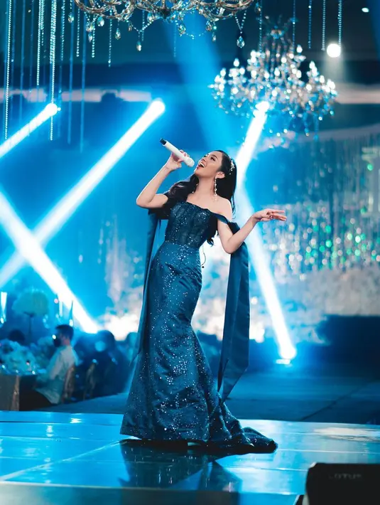 Tampil menyanyi di atas panggung, Lyodra megenakan off sholder pegged dress berwarna biru, yang dipenuhi payet untuk menambah kesan mewah. Di bagin lengan dress juga diberi sayap panjang sebagai pemanis. Foto: Instagram.