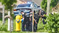 Sederet petugas polisi mencari bukti di lokasi kecelakaan mobil di London, Ontario pada Senin, 7 Juni 2021. Polisi mengatakan banyak orang tewas setelah beberapa pejalan kaki ditabrak mobil pada Minggu malam. (Geoff Robins/The Canadian Press via AP)