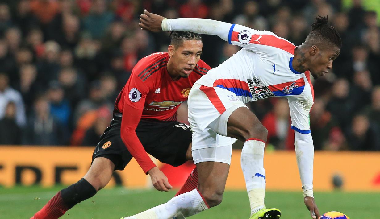 Gelandang Crystal Palace, Wilfed Zaha saat mencoba melewat Chris Smalling pada laga lanjutan Premier League yang berlangsung di stadion Old Trafford, Manchester, Minggu (25/11). Crystal Palace bermain imbang 0-0. (AFP/Lindsay Parnaby)