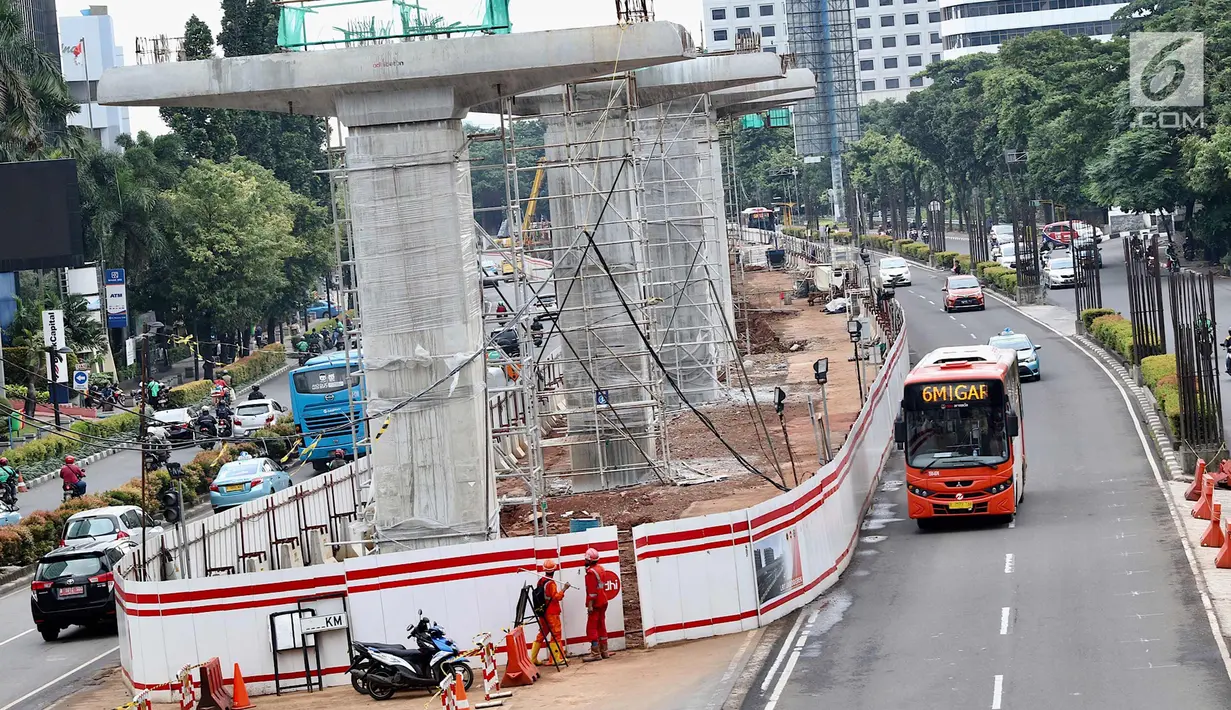 Bus transjakarta melintas di samping proyek LRT di kawasan Kuningan, Jakarta Selatan, Rabu (21/2). Presiden Jokowi meminta semua proyek konstruksi layang (elevated) dihentikan sementara. (Liputan6.com/Immanuel Antonius)