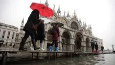 Sejumlah warga berjalan melewati papan saat gelombang pasang membuat banjir depan Basilika Santo Markus, Venesia, Italia, Selasa (12/11/2019). Venesia dilanda banjir akibat gelombang pasang setinggi 127 cm. (AP Photo/Luca Bruno)