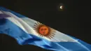 Gerhana bulan terlihat di belakang bendera Argentina saat blood moon pertama tahun ini di Buenos Aires, Argentina, Senin (16/5/2022). (AP Photo/Rodrigo Abd)