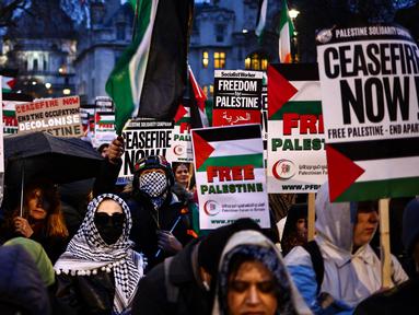 Para demonstran pro-Palestina melambaikan bendera Palestina dan memegang plakat saat berunjuk rasa di Parliament Square, London pada 21 Februari 2024. (HENRY NICHOLLS/AFP)