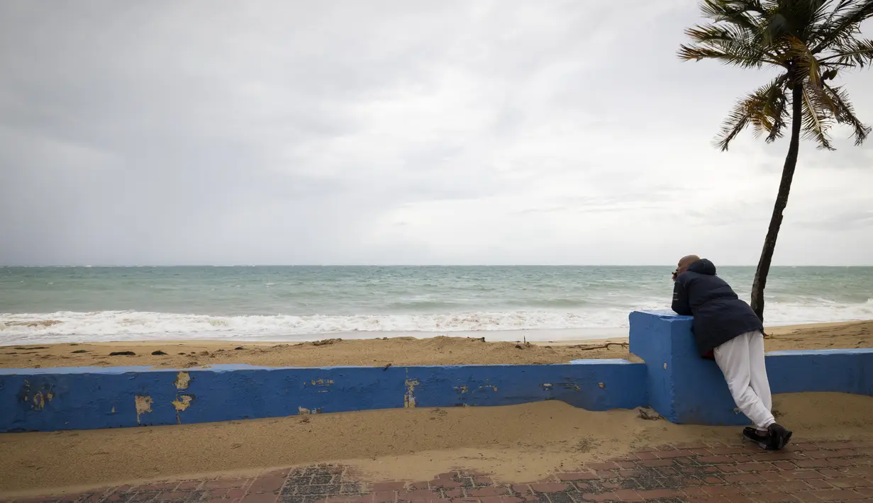 Seorang pria berdiri di dekat pantai sebelum kedatangan Badai Tropis Fiona di San Juan, Puerto Rico, Sabtu (17/9/2022). Fiona diperkirakan akan menjadi badai saat mendekati Puerto Rico dan akan melintasi wilayah teritori Amerika Serikat pada Minggu pagi. (AP Photo/Alejandro Granadillo)