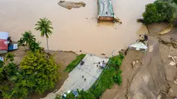 Sebagian badan jembatan ambruk dan terputus membuat arus lalu lintas lumpuh total. Tampak foto udara menunjukkan jembatan yang rusak akibat banjir bandang di jalan utama yang menghubungkan Aceh dan Sumatera Utara di Meureudu, Kabupaten Pidie Jaya, Provinsi Aceh, pada Jumat 28 November 2025. (CHAIDEER MAHYUDDIN/AFP)