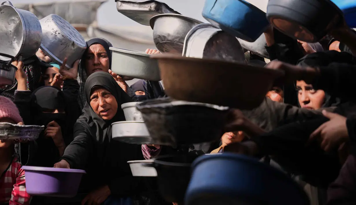 Meski sejak 2 Februari 2026, perbatasan Rafah dibuka, secara sangat terbatas untuk pergerakan orang, hanya memberikan sedikit harapan bagi akses logistik. Tampak dalam foto, perempuan Palestina berebut menerima makanan sumbangan di dapur umum, Khan Younis, Jalur Gaza selatan, Jumat 6 Februari 2026. (AP Photo/Abdel Kareem Hana)