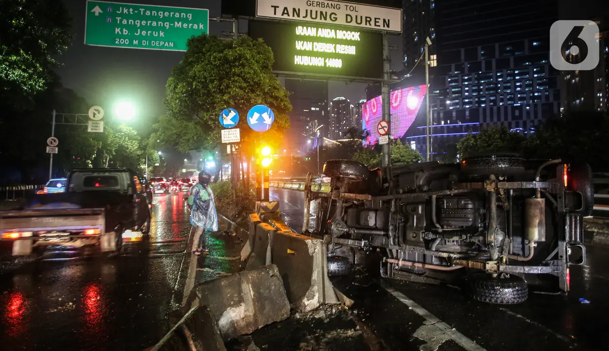 Pengguna jalan menonton mobil jenis jeep yang terguling di depan gerbang Tol Tanjung Duren, Jalan S Parman, Jakarta Barat, Minggu (26/9/2021). Tidak ada korban jiwa, namun kecelakaan tersebut membuat lalu lintas di jalan itu terimbas kemacetan yang cukup panjang. (Liputan6.com/Johan Tallo)