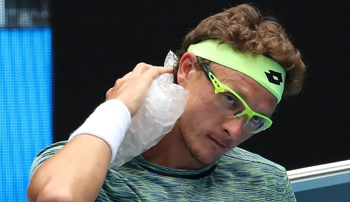 Petenis asal Uzbekistan, Denis Istomin meletakkan handuk ber isi es di lehernya saat istirahat dalam pertandingan melawan petenis Bulgaria, Grigor Dimitrov pada kejuaraan tenis Australia Terbuka di Melbourne, Australia, (22/1). (AP Photo/Aaron Favila)