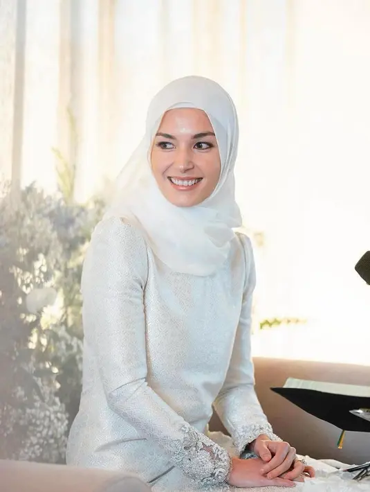 Potret memesona Yang Mulia Dayang Anisha Rosnah binti Adam saat acara Khatam Quran beberapa hari lalu. Ia mengenakan baju kurung dengan detail motif tenun Brunei yang rumit, berwarna putih, dipadukan dengan gaya kerudung sederhana yang juga berwarna putih polos. [Foto: Instagram/anis.haikk]