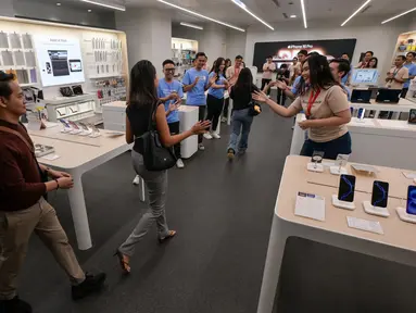 Para karyawan menyambut pelanggan yang memasuki toko mereka yang menjual Apple iPhone 16 di Jakarta pada 11 April 2025. (BAY ISMOYO/AFP)