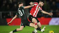 Gelandang Liverpool, Tyler Morton (kiri), berebut bola dengan bek Southampton, Ryan Manning, dalam laga perempat final Carabao Cup di St Mary's Stadium, 18 Desember 2024. (JUSTIN TALLIS / AFP)