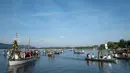 Warga Desa Moos memasuki Pelabuhan Radolfzell sambil manaiki kapal berhias bunga saat mengikuti Pawai Air Mooser di Danau Constance, Jerman, Senin (22/7/2019). Para peserta mengenakan kostum tradisional saat mengikuti Pawai Air Mooser. (Patrick Seeger/DPA/AFP)