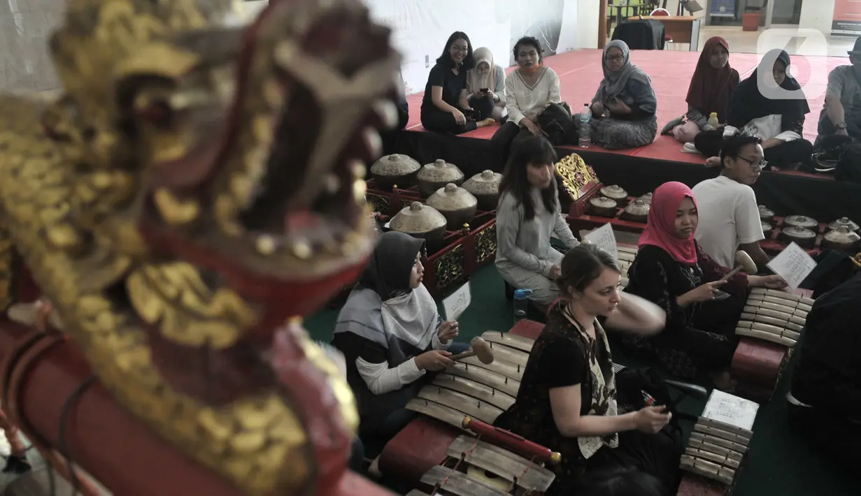 Wisatawan asing berlatih menjadi Nayaga saat lokakarya "Suara Dari Masa Lalu" di Museum Nasional, Jakarta, Minggu (22/12/2019). Lokakarya ini bertujuan mengenalkan sejarah gamelan dan mengajak generasi muda atau milenial mampu melestarikan musik tradisional Indonesia. (merdeka.com/Iqbal S. Nugroho)