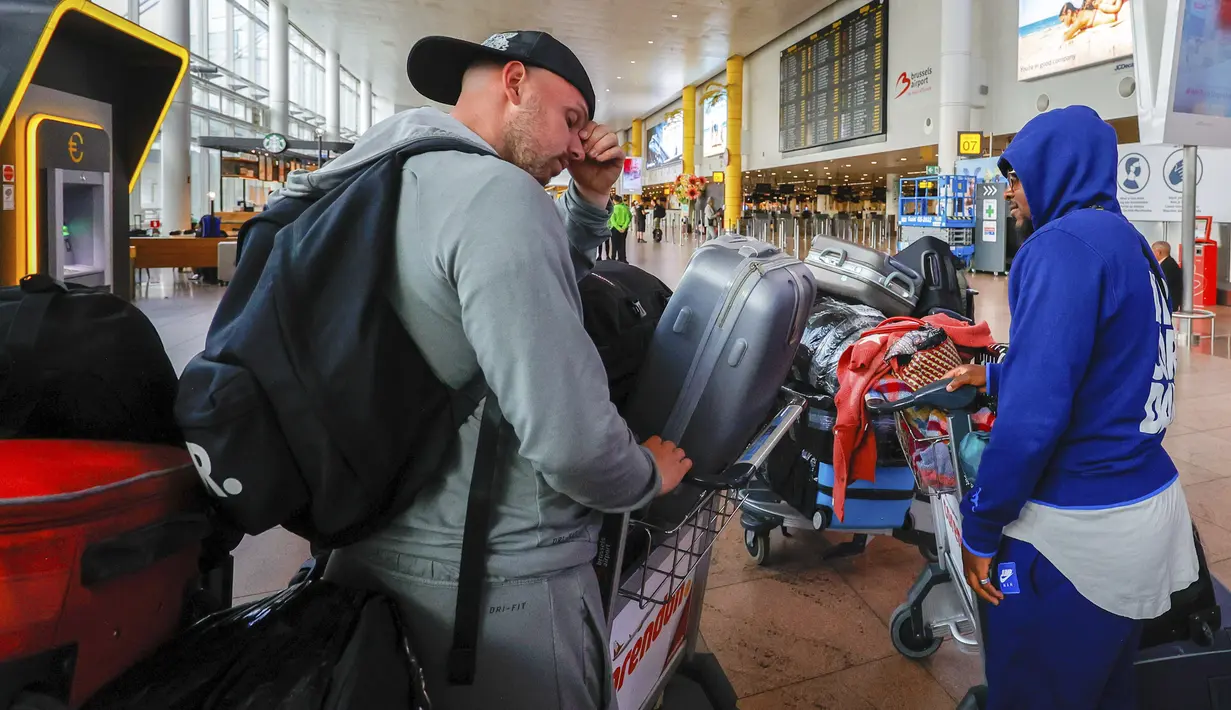 Dua penumpang berjalan di ruang keberangkatan di bandara internasional Brussel dengan barang bawaan mereka selama pemogokan nasional di Brussel, Belgia, Senin (20/6/2022). Penumpang diimbau untuk tidak datang ke bandara dan memesan ulang penerbangan mereka. (AP Photo/Olivier Matthys)