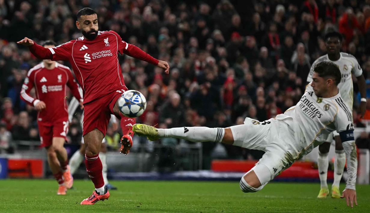 Penyerang Liverpool asal Mesir, Mohamed Salah (kiri) berebut bola dengan gelandang Real Madrid asal Uruguay, Federico Valverde dalam pertandingan pekan keempat Liga Champions 2025-2026 di Stadion Anfield, Inggris, pada Selasa 4 November 2025 waktu setempat atau Rabu (5/11/2025) dini hari WIB. Namun pertahanan rapat Liverpool berhasil menahan gempuran pemain Real Madrid. (Paul ELLIS/AFP)
