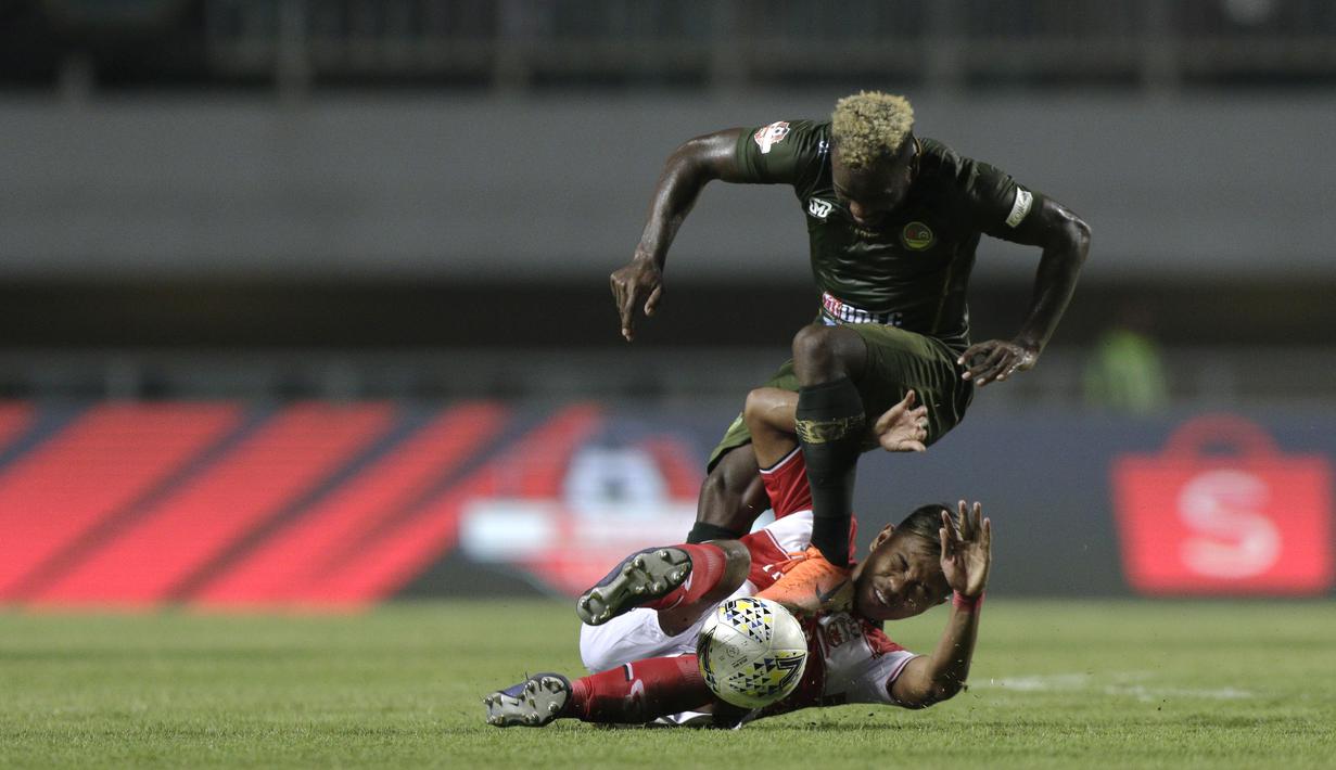 Gelandang PS Tira Persikabo, Parfair Essengue, berebut bola dengan pemain Madura United pada laga Shopee Liga 1 di Stadion Pakansari, Bogor (12/7). Tira bermain imbang 2-2 atas Madura. (Bola.com/Yoppy Renato)