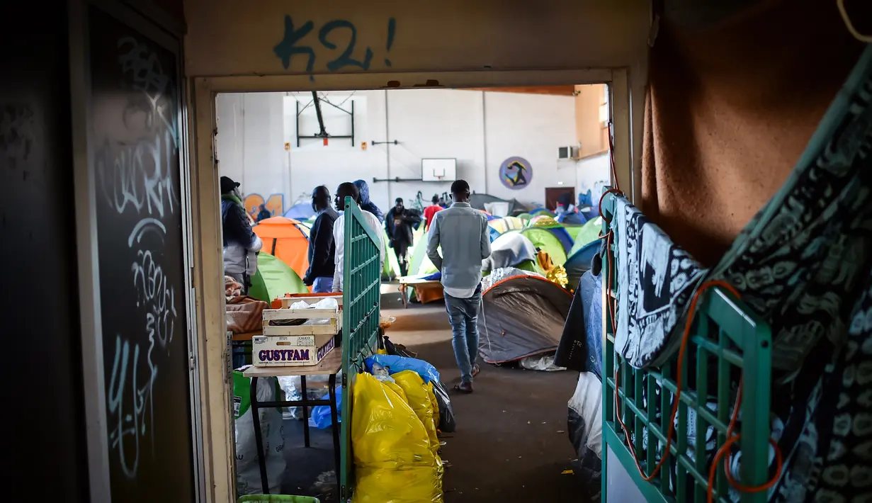 Seorang pria berjalan di gimnasium yang ditempati oleh para migran di lycee Jeanne-Bernard di Saint-Herblain, di luar Nantes, Prancis barat (28/3). Sekitar 250 imigran saat ini tinggal di tempat tersebut. (AFP Photo/Loic Venance)