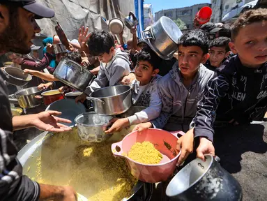 Orang-orang berebut untuk mendapatkan makanan hangat di kamp pengungsi Palestina, Nuseirat, Jalur Gaza Tengah pada Kamis 7 Mei 2026. Krisis kemanusiaan di Gaza per Mei 2026 mencapai titik kritis. (Eyad Baba/AFP)