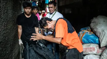 Gambar yang diambil pada 1 September 2016 menunjukkan kesedihan seorang ayah dari pengguna narkoba saat petugas mengevakuasi jasad anaknya yang diduga tewas dibunuh oleh polisi di Manila, Filipina. (AFP PHOTO/Noel CELIS)