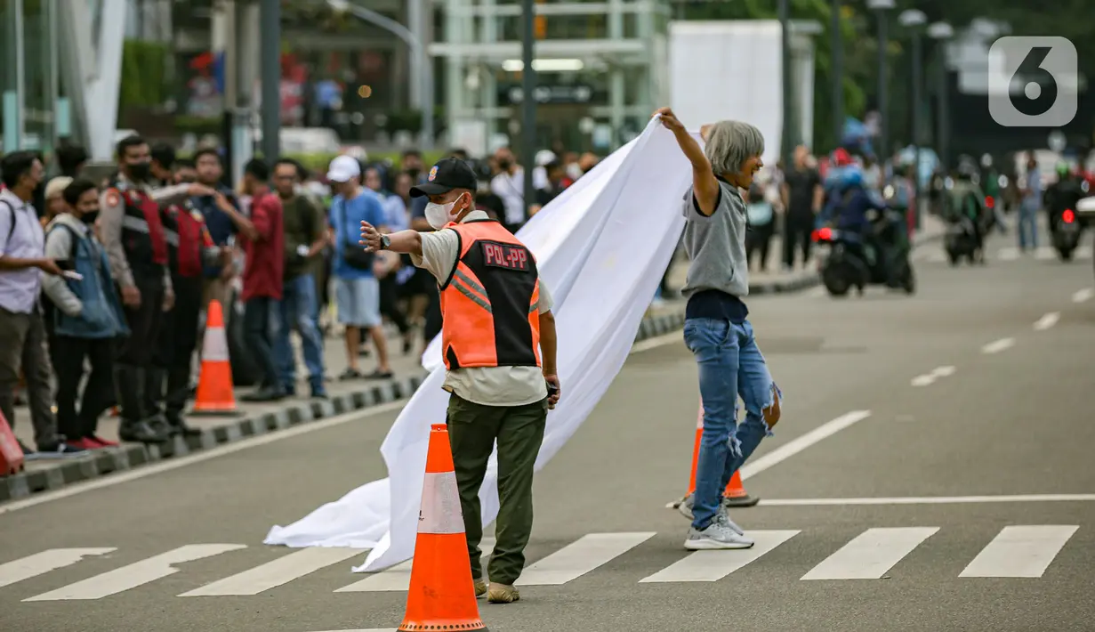 Personel gabungan dari unsur polisi hingga Satpol PP mengatur lalu lintas di kawasan zebra cross Dukuh Atas, Jakarta, Rabu (27/7/2022). Mereka dikerahkan untuk memantau kegiatan peragaan busana Citayam Fashion Week (CFW) guna meminimalisir terjadinya kriminalitas, kemacetan, hingga parkir liar. (Liputan6.com/Faizal Fanani)