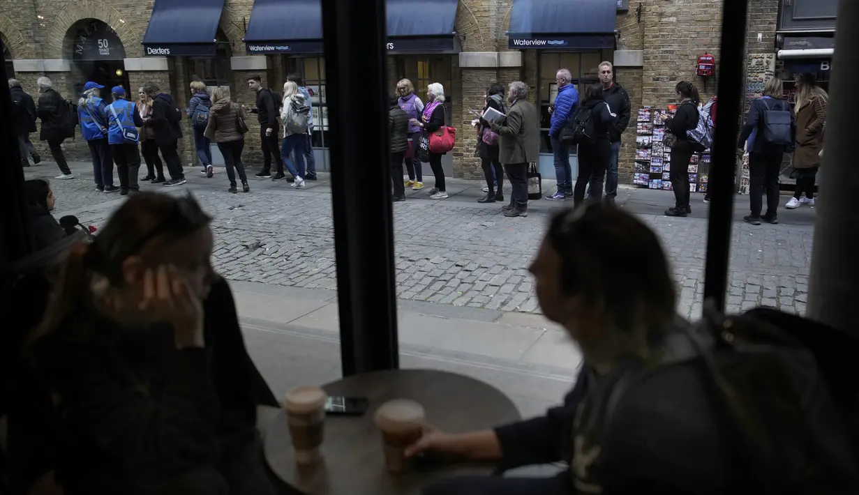 <p>Perempuan meminum kopi di bar saat orang mengantre di luar untuk menghormati mendiang Ratu Elizabeth II, yang terbaring di Westminster Hall, London pada 16 September 2022. Ratusan ribu orang diperkirakan akan memberikan penghormatan kepada ratu menjelang pemakaman kenegaraannya, mendorong permintaan kamar hotel di pusat kota London yang dalam beberapa kasus harganya naik dua kali lipat. (AP Photo/Christophe Ena)</p>
