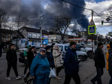 Orang-orang mengantre di depan supermarket sementara asap mengepul di atas kota Vasylkiv di luar Kiev (27/2/2022). Rudal Rusia telah menghantam pipa gas dan kilang minyak di kawasan Vasylkiv. (AFP/Dimitar Dilkof)