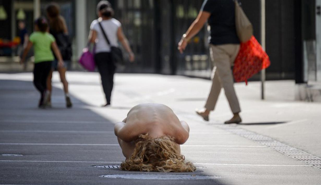Seorang wanita tanpa busana melakuka aksi di jalanan Kota Biel, Swiss, Jumat (21/8/2015). Aksi ini merupakan festival pertunjukan telanjang pertama di dunia yang mereka adakan di muka umum. (AFP PHOTO/Fabrice Coffrini)