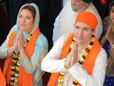 Perdana Menteri Kanada Justin Trudeau (kanan) bersama istrinya Sophie Gregoire (kiri) memberi penghormatan di Kuil Emas Sikh di Amritsar, India (21/2). Trudeau dan istri memakai busana khas India saat mengunjungi kuil tersebut. (AFP Photo/Narinder Nanu)