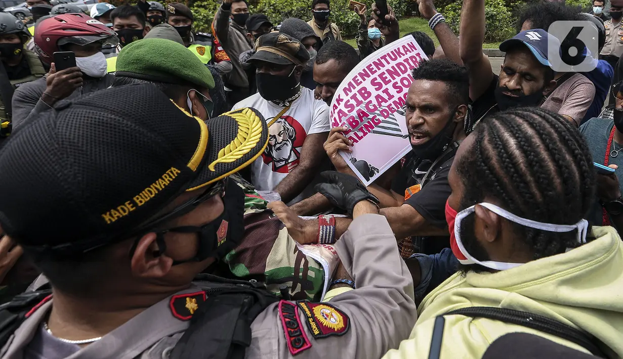 Polisi dan tentara saling dorong dengan masyarakat Papua yang memperingati Operasi Trikora 19 Desember 1961 di Patung Kuda, Jakarta, Sabtu (19/12/2020). Salah satu tuntutan massa adalah penghentian segala bentuk diskriminasi dan intimidasi terhadap mahasiswa Papua Barat. (Liputan6.com/Johan Tallo)