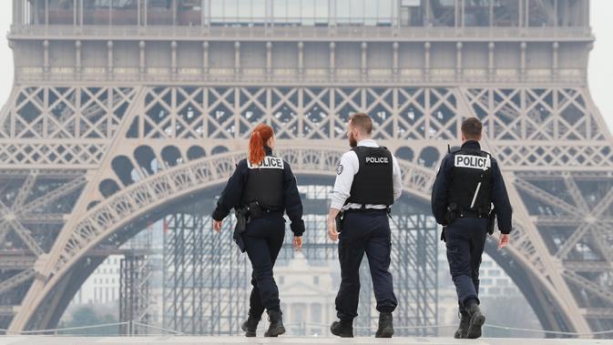 Polisi menyisir area lapangan Esplanade du Trocadero dekat Menara Eiffel saat lockdown di Paris, Prancis, Rabu (18/3/2020). Sampai Selasa (17/3/2020), Prancis memiliki 6.633 kasus virus corona COVID-19 dengan 148 kematian. (Ludovic MARIN/AFP)