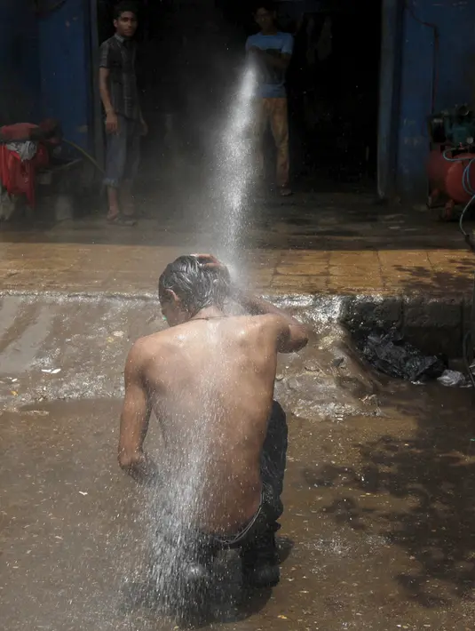 Seorang pria mendinginkan tubuhnya di bawah guyuran air saat cuaca panas yang ekstrem di Karachi, Pakistan, (23/6/2015). Gelombang panas yang telah menewaskan lebih dari 400 jiwa di kota selatan Pakistan. (REUTERS/Akhtar Soomro)