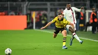 Penyerang AC Milan, Rafael Leao (kiri) berebut bola dengan bek Borussia Dortmund, Nico Schlotterbeck, pada matchday 2 Grup F Liga Champions 2023/2024 di Signal Iduna Park, Kamis (5/10/2023) WIB. (INA FASSBENDER / AFP)