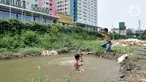 Anak-anak berenang di kubangan air di depan Apartemen Green Pramuka, Jakarta, Rabu (5/2/2020). Keterbatasan ekonomi dan minimnya lahan bermain membuat sekelompok anak sekolah dasar ini memilih berenang di kubangan meskipun mereka tahu air kotor dapat menimbulkan penyakit. (merdeka.com/Iqbal Nugroho)