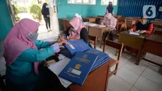 Guru Wali Kelas mengenakan masker membagikan raport di SMP Negeri 18 Tangerang Selatan, Banten, Kamis (17/12/2020). Pengambilan hasil raport belajar mengajar secara online di masa pandemi Covid-19 guru mempertanyakan perkembangan siswa ke wali murid selama belajar di rumah. (merdeka.com/Dwi Narwoko)