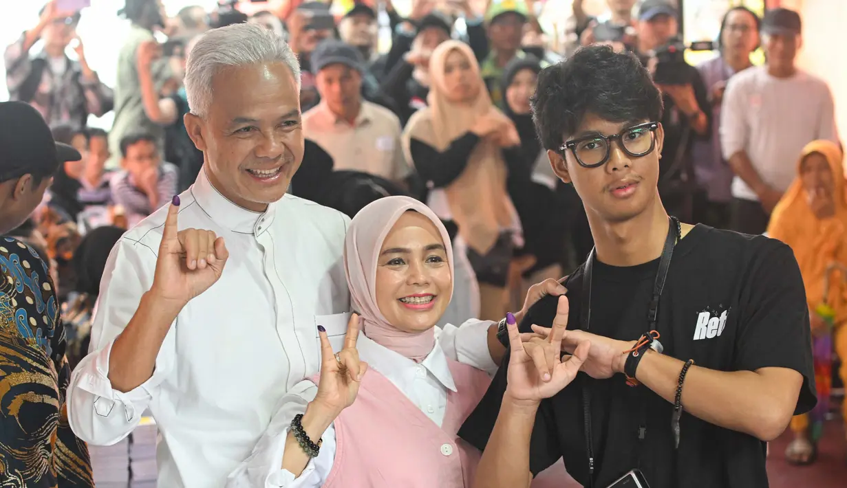 <p>Calon Presiden nomor urut 3, Ganjar Pranowo bersama istrinya Siti Atiqoh Supriyanti dan putranya Muhammad Zinedine Alam Ganjar (kiri ke kanan) menunjukkan jari-jari mereka usai memberikan suara dalam pemilihan umum (Pemilu) serentak 2024 di Semarang, Jawa Tengah pada 14 Februari 2024. (JUNI KRISWANTO/AFP)</p>